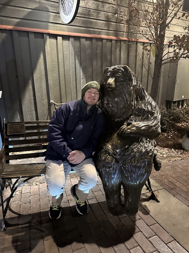 Brandon on a bench with a statue of a bear
